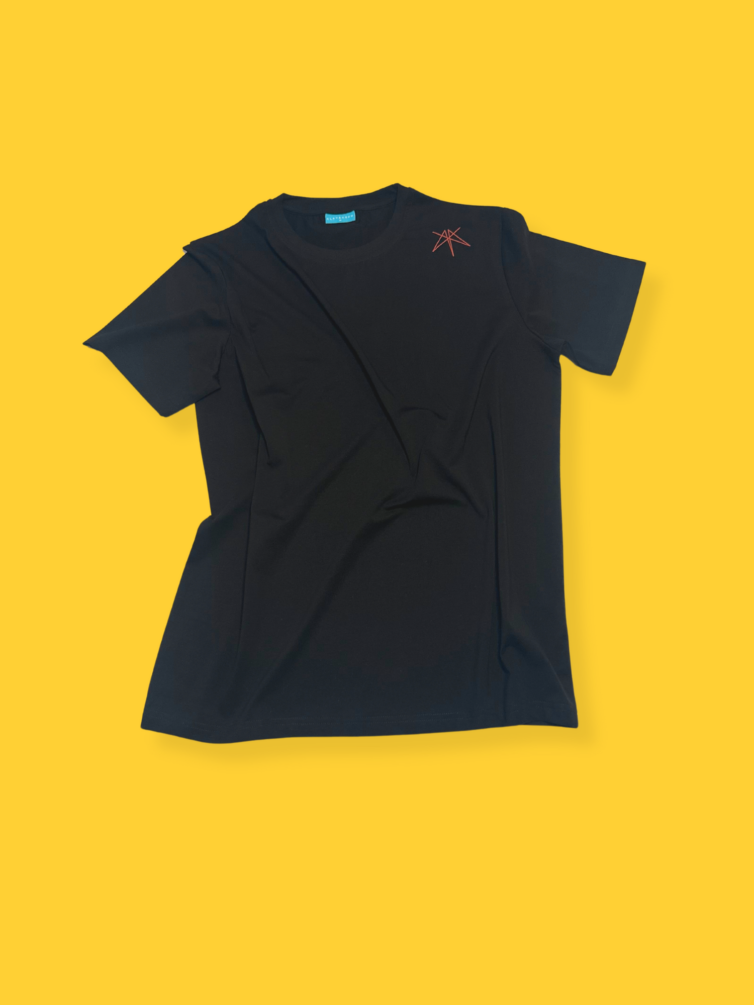 Clay & Ash black T-shirt displayed on a vibrant yellow background, highlighting the brand’s logo on the chest and sleek fit.